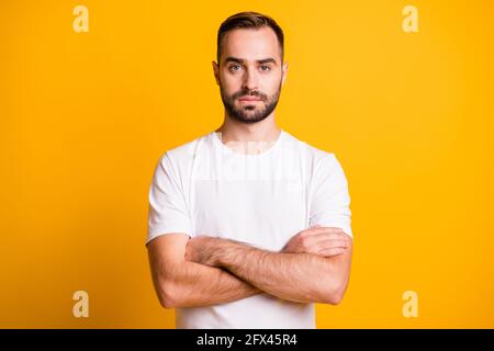 Portrait de gentil sérieux barbu gars entraîneur de gym les bras pliés isolé sur fond jaune vif Banque D'Images