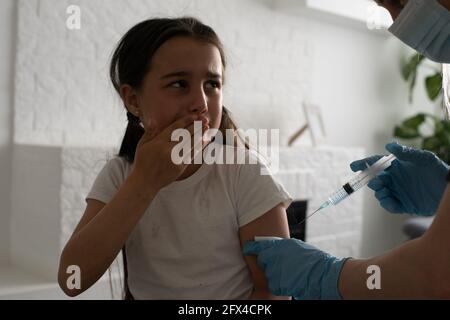 Une petite fille avec des larmes dans les yeux a très peur de la vaccination. Le bébé pleure la douleur en fermant les yeux. Portrait d'un enfant qui l'est Banque D'Images