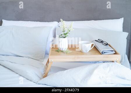 Petit-déjeuner dans le décor de maquette de papeterie de lit. Tasse de café, journal et verres sur plateau vase blanc avec petites fleurs. Saint-Valentin petit déjeuner, vie Banque D'Images