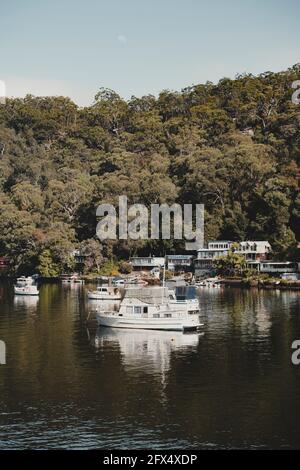 Bateaux sur l'eau devant des maisons idylliques en bord de mer à Berowra Waters, Nouvelle-Galles du Sud. Comme vu de la Great North Walk. Banque D'Images