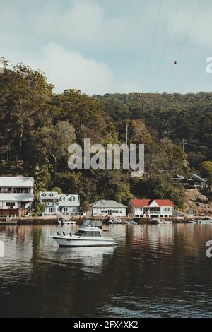 Bateaux sur l'eau devant des maisons idylliques en bord de mer à Berowra Waters, Nouvelle-Galles du Sud. Comme vu de la Great North Walk. Banque D'Images