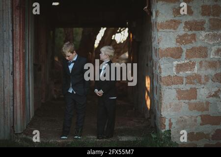 Adorables garçons australiens portant des costumes noirs debout à côté les uns des autres dans la campagne Banque D'Images