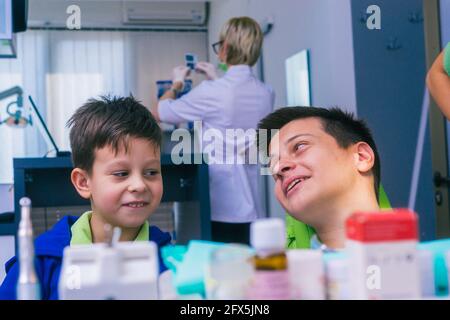 Deux jeunes frères heureux assis dans un bureau de dentiste et attendant un examen dentaire Banque D'Images