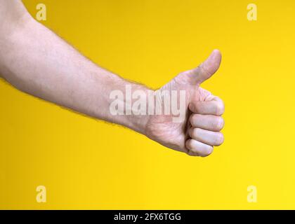 Main de l'homme avec le pouce vers le haut isolée sur fond jaune. Afficher comme, signe positif. Symbole, icône de Perfect ou accepter. Banque D'Images