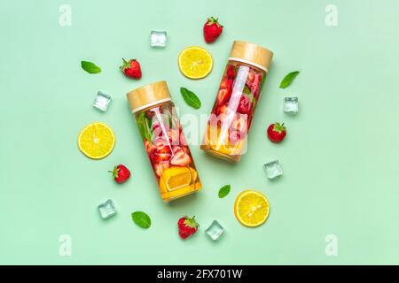 Eau, cocktail, limonade ou thé infusés à la fraise. Boisson fraîche glacée d'été avec fraise, citron et lef de menthe sur fond vert. Pose à plat Banque D'Images