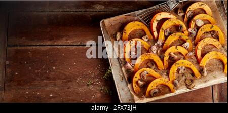 De dessus de savoureux plat vegan avec des tranches de citrouille et champagnes hachés rôtis aux épices aromatiques sur plaque à pâtisserie sur une table en bois Banque D'Images