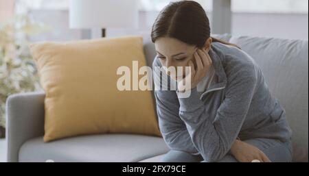 Triste femme dépressive assise sur le canapé auto-isolant à la maison Banque D'Images