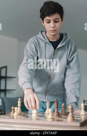 Smart Kid jouant des échecs et des pièces en mouvement sur l'échiquier, les loisirs et le concept de jeux Banque D'Images