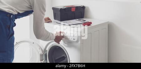 Réparateur réparant une machine à laver, il règle un bouton, un concept de service professionnel Banque D'Images