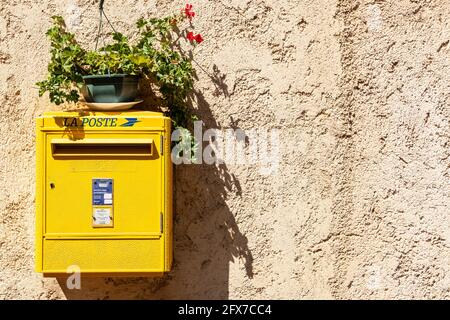 Boîte postale jaune la poste française, avec un pot de fleurs Banque D'Images