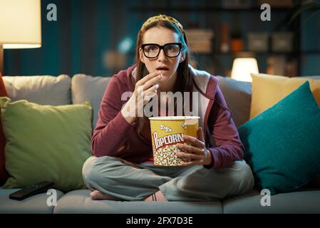 Femme regardant un film de suspense et mangeant du pop-corn Banque D'Images