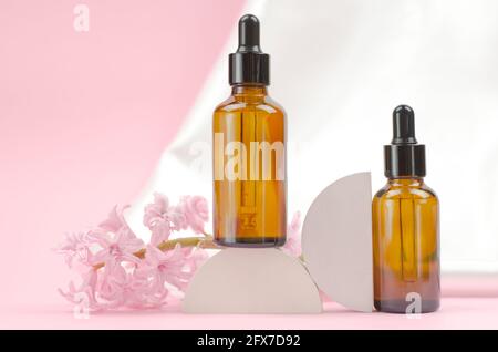 Deux flacons bruns avec compte-gouttes avec huiles essentielles ou sérum avec fleurs de jacinthe. Concept de soins et de beauté Banque D'Images