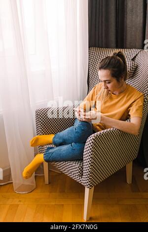 La jeune femme s'est concentrée sur son smartphone assis dans le fauteuil Banque D'Images