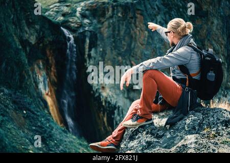 L'homme voyageur est assis sur une pierre dans les montagnes Banque D'Images