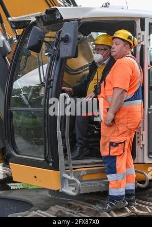 26 mai 2021, Brandebourg, Guben : Axel Vogel (l., Bündnis 90/Die Grünen), ministre de l'Agriculture, de l'Environnement et du climat de l'État de Brandebourg, et Thomas Matz, machiniste de la compagnie Meyer Bau, ont symboliquement commencé la cérémonie révolutionnaire pour l'expansion de la protection contre les inondations sur la rivière frontière Neisse à l'aide d'une pelle hydraulique avec un conducteur de pieux. Cela permettra d'améliorer encore la protection contre les inondations dans la ville. À l'heure actuelle, la digue existante et le mur de remblai dans la zone du Plastinarium, qui a grand besoin de rénovation, ne fournissent pas une protection suffisante contre les inondations pour l'ur Banque D'Images