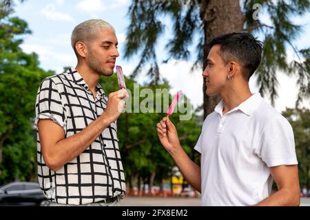 Heureux couple gay d'Amérique latine ayant glace dans un parc de la ville. Banque D'Images