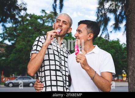 Heureux couple gay d'Amérique latine ayant glace dans un parc de la ville. Banque D'Images