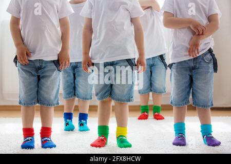 Pieds d'enfants avec différentes chaussettes debout dans les rangs, les enfants portant différentes chaussettes colorées Banque D'Images