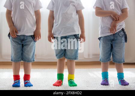 Pieds d'enfants avec différentes chaussettes debout dans les rangs, les enfants portant différentes chaussettes colorées Banque D'Images