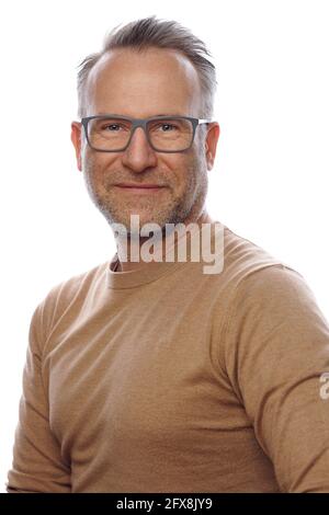 Souriant sympathique non rasé homme d'âge moyen en vêtements de loisirs portant des lunettes tournant pour regarder l'appareil photo dans un portrait du haut du corps sur blanc Banque D'Images