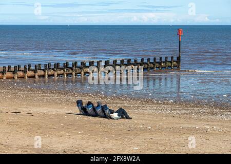 Quatre personnes bronzer au milieu du mois d'avril près de la mer du Nord à Bridlington, East Riding of Yorkshire, Angleterre Royaume-Uni. Version noir et blanc 2FX8TYW Banque D'Images