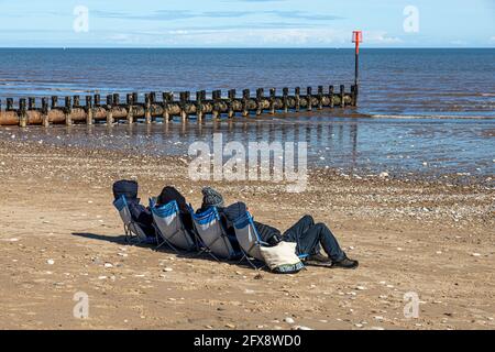 Quatre personnes bronzer au milieu du mois d'avril près de la mer du Nord à Bridlington, East Riding of Yorkshire, Angleterre Royaume-Uni. Version noir et blanc 2FX8WA1 Banque D'Images