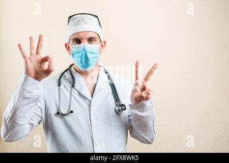 Le médecin dans le masque et les lunettes montre deux doigts. Photo de haute qualité Banque D'Images