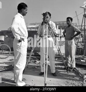 1957, historique, sur le site de construction du projet d'acier de Durgapur, Durgapur, Bengale-Occidental, Inde, arpenteurs indiens utilisant un théodolite microptique no 1 Hilger & Watts sur un trépied. Instrument optique de précision pour mesurer les angles entre les points visibles sur les plans horizontal et vertical, traditionnellement utilisé pour l'arpentage, cette théodolite de transit a également été largement utilisée dans la construction de bâtiments et d'infrastructures. La construction de l'usine d'acier de Durgapur a été l'un des premiers grands projets de construction en inde après avoir obtenu l'indépendance de la Grande-Bretagne. Banque D'Images