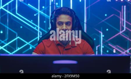 Joueur professionnel de eSports jouant dans des jeux vidéo d'ordinateur. Graphismes élégants en arrière-plan. Événement de streaming de tournoi de championnat en ligne. Portrait Banque D'Images