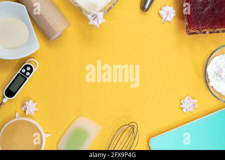 Outils et ingrédients pour faire de la meringue : thermomètre, fouet, spatule, parchemin, sucre, bourrage, buse métallique. Vue de dessus. Arrière-plan jaune avec espace Banque D'Images