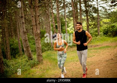 Un jeune couple de remise en forme court sur le sentier forestier par une journée d'été Banque D'Images