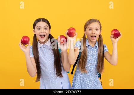 Les enfants heureux tiennent des pommes pour une collation saine de retour à l'école fond jaune, l'alimentation scolaire Banque D'Images