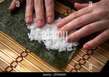 les mains tortillent les petits pains à sushis. gros plan. méthode de cuisine japonaise Banque D'Images