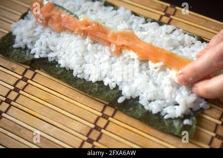 les mains tortillent les petits pains à sushis. gros plan. méthode de cuisine japonaise Banque D'Images