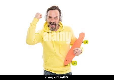 homme heureux écouter de la musique dans les écouteurs tenir penny skateboard isolé sur blanc, skateboard hobby. Banque D'Images