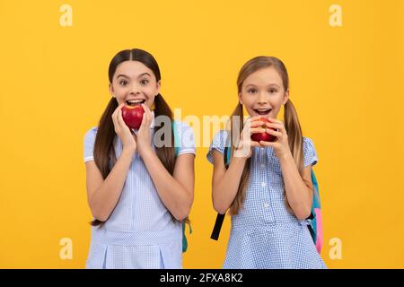 Les adolescents heureux à l'école les enfants mangent de la vitamine bio pommes fond jaune, la nutrition scolaire Banque D'Images