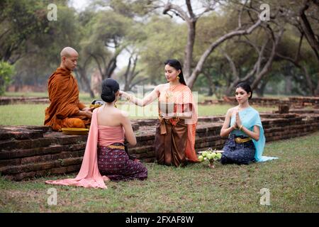 Femme thaïlandaise rendent hommage à un moine bouddhiste au matin. Banque D'Images