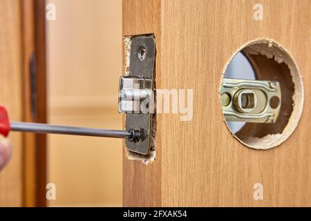 Remplacement de la serrure de porte par une poignée et du loquet par une nouvelle. Banque D'Images