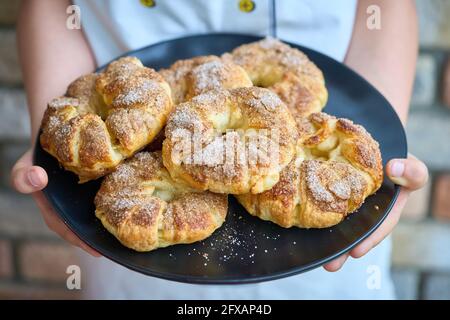 Un garçon tenant une assiette avec des gâteaux faits maison dans ses mains. Banque D'Images