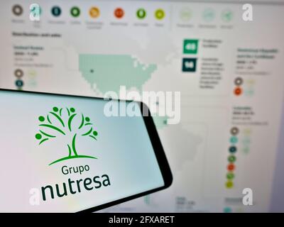 Téléphone portable avec logo de la société colombienne de transformation des aliments Grupo Nutresa S.A. sur écran devant le site. Mise au point au centre-gauche de l'écran du téléphone. Banque D'Images