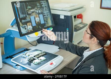 Woman examine les microcircuits sur un appareil spécial pour la lecture des malvoyants. Banque D'Images