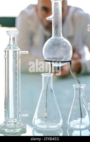 Un scientifique de sexe masculin cherche à porter une blouse de laboratoire avec des flacons en verre dans un laboratoire scientifique. Pays basque, Espagne, Europe. Banque D'Images