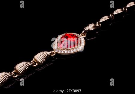 bracelet doré avec rubis et diamants isolés sur noir Banque D'Images