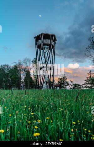 Tour d'observation appelée Na Vetrne Horce au coucher du soleil, région de Broumov, République Tchèque.Tour en bois avec escalier en spirale sur la floraison prairie fraîche scène de printemps Banque D'Images