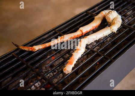 Cuisson des pattes de homard sur un gril en fer sur des plats chauds Banque D'Images