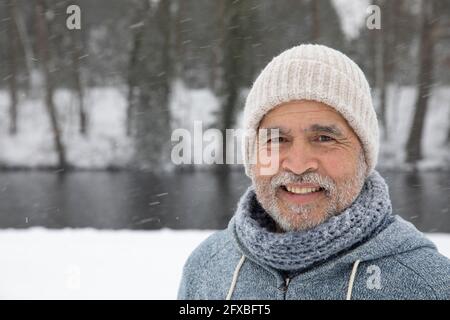 Homme senior portant un chapeau en tricot souriant pendant l'hiver Banque D'Images