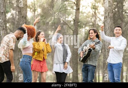 Des amis gais et multiethniques dansent et s'amusant dans la forêt Banque D'Images