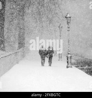 Couple marchant ensemble dans un parc couvert de neige pendant une forte chute de neige Banque D'Images