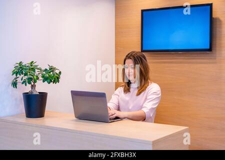 Réceptionniste travaillant sur un ordinateur portable au bureau de la clinique Banque D'Images
