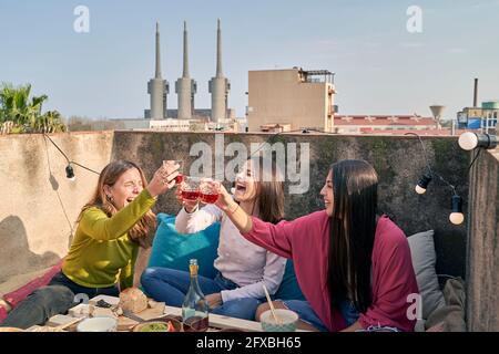 Des amies rient tout en dorant un verre de vin sur le toit Banque D'Images